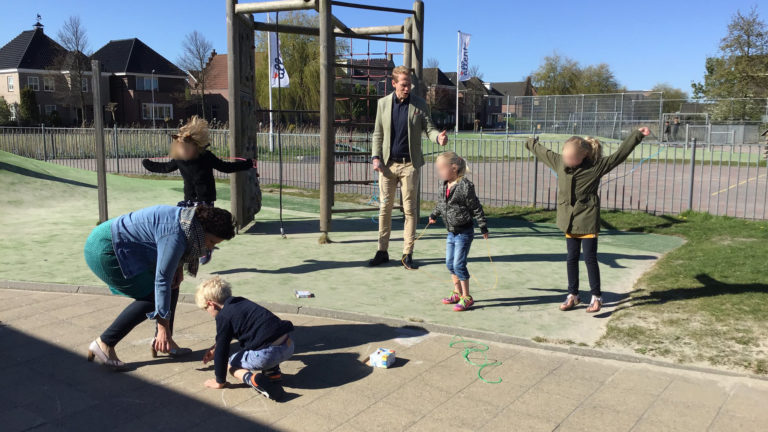 Wethouder Langendijk met stoepkrijt en springtouwen op bezoek bij de noodopvang