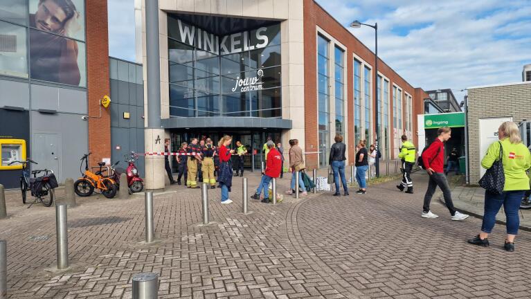 Mensen staan buiten een winkelcentrum dat door de brandweer is afgezet.