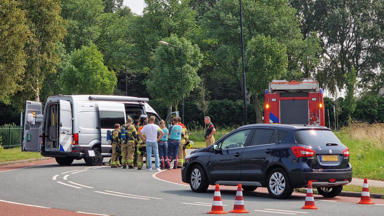 Hulpverleners aan het werk bij een ongeval met meerdere voertuigen, waaronder een camper en een brandweerwagen, op een weg omgeven door groen.