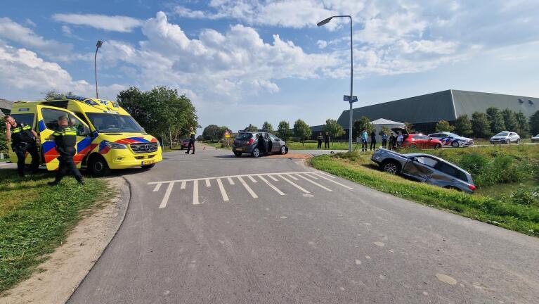 Verkeersongeval met meerdere auto's, politie en ambulance ter plaatse op een landelijke weg.