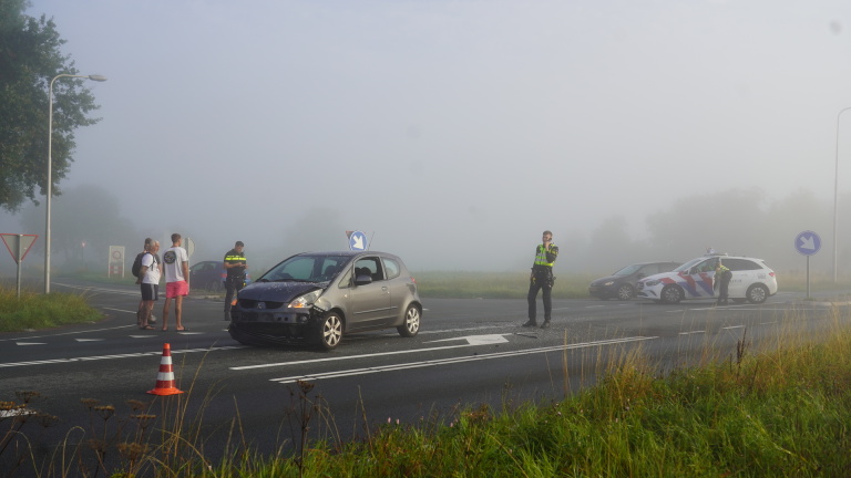 Auto-ongeluk op een mistige weg met politieagenten en omstanders.