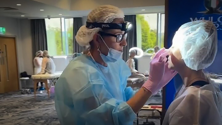 Een medisch specialist met beschermende kleding behandelt een patiënt in een kliniek.