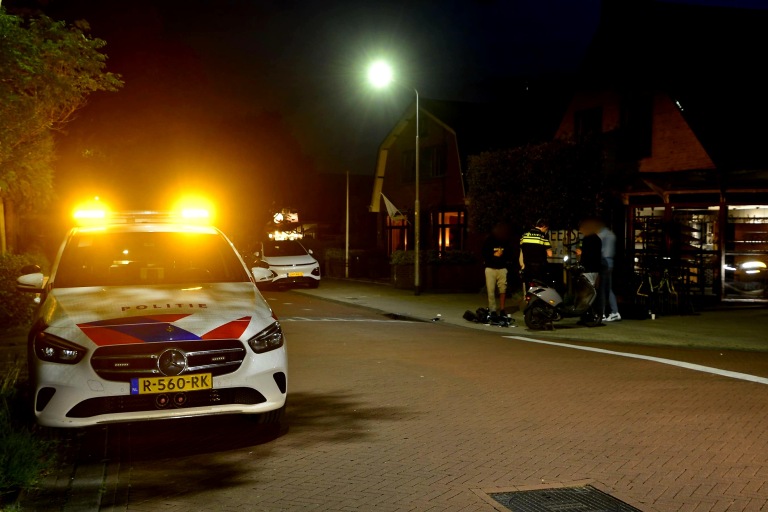 Politieauto met knipperende lichten bij nachtelijk incident met scooter en agenten.