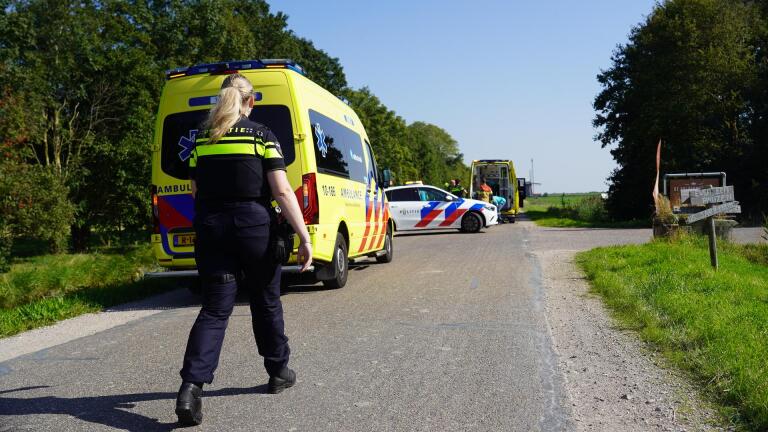 Een politieagent loopt naar een ongevalslocatie met een ambulance en politieauto.