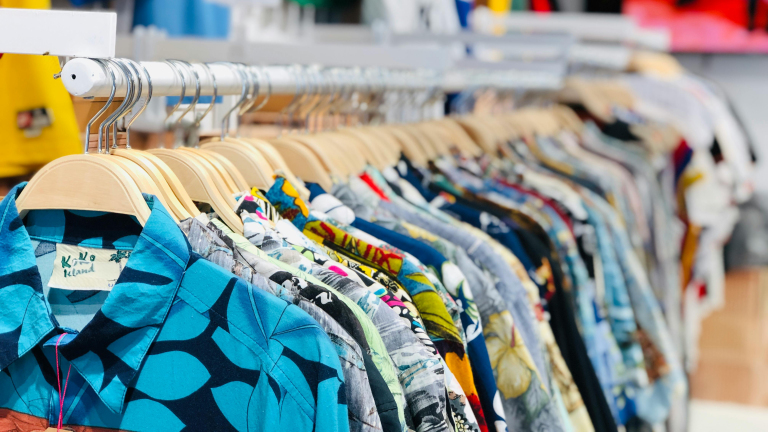 Kleurrijke overhemden op houten hangers in een kledingwinkel.