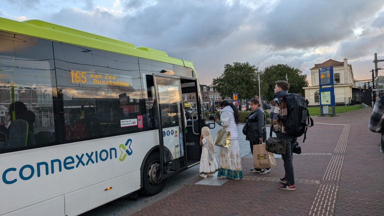 Een groep mensen die instappen in een Connexxion-bus 165 richting Zee Busstation bij een halte.