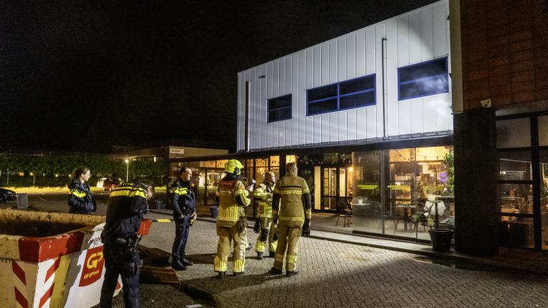 Politie- en brandweermensen voor een goed verlicht gebouw tijdens de nacht.