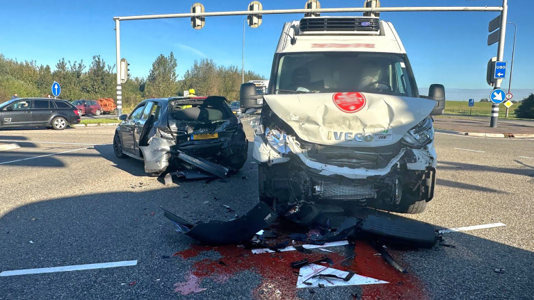 Verkeersongeval met een zwaar beschadigde auto en een bestelwagen op een kruispunt met verkeerslichten.