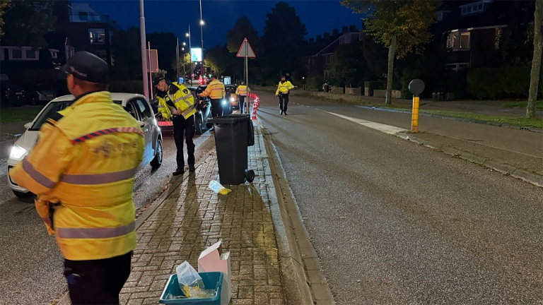 Verkeerscontrole door politieagenten in gele jassen langs een weg in de avond.