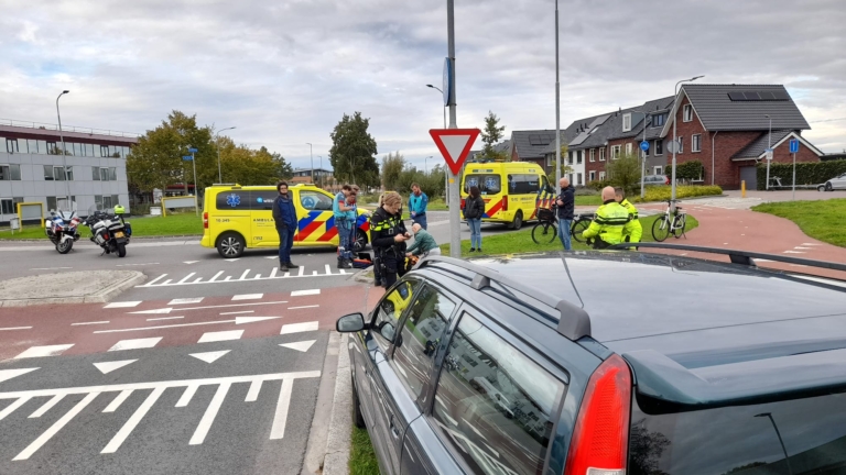 Hulpverleners en politie bij een ongeluk met ambulance en motor op een kruispunt.