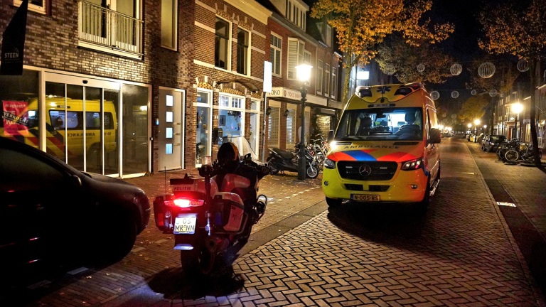 Politievoertuig en ambulance in een verlichte straat 's nachts.