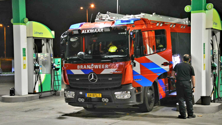 Brandweerwagen in Alkmaar tankt bij een benzinestation terwijl een medewerker toekijkt.