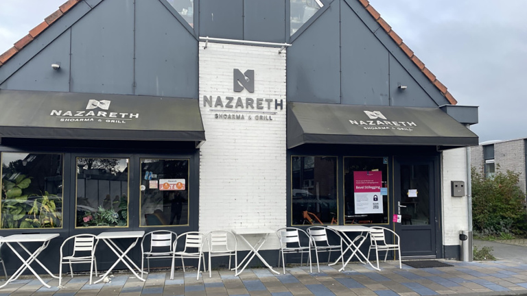 Vooraanzicht van restaurant Nazareth Shoarma & Grill met terrasstoelen en tafels buiten.