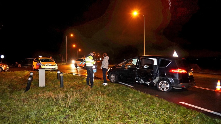 Botsing tussen twee auto's bij nacht; politie en betrokkene bezig met onderzoek.