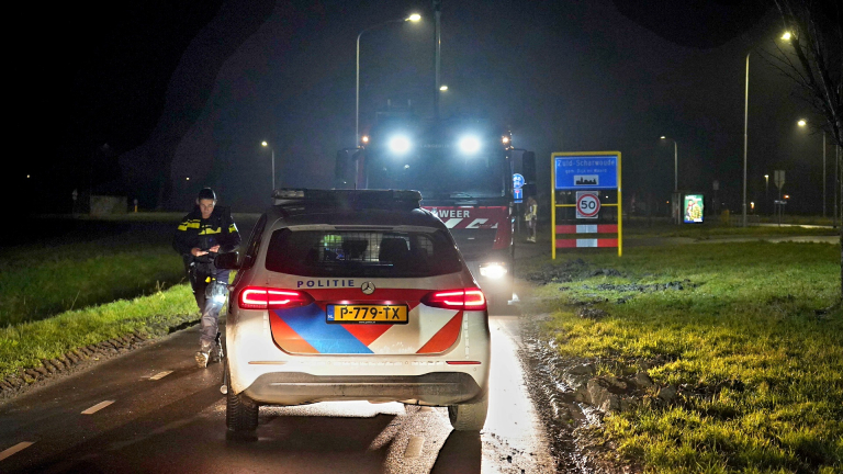 Nachtelijke scene met politieauto en brandweerwagen bij een verkeersteken in Zuid-Scharwoude.