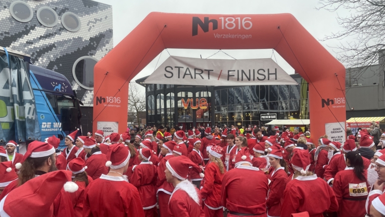 Mensen gekleed als kerstmannen verzamelen zich bij de start/finish lijn van een evenement.