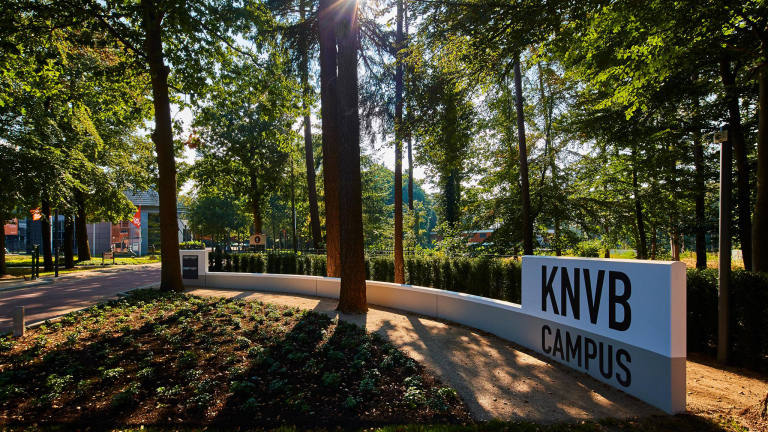 KNVB Campus ingang omringd door bomen en groen.