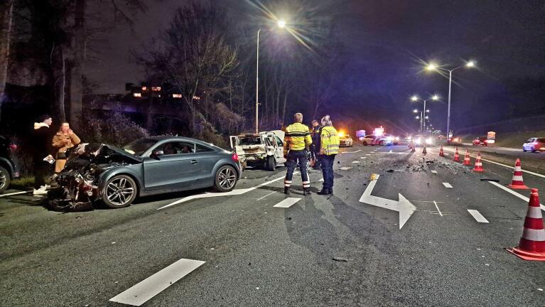 Verkeersongeval op een snelweg 's nachts, met politie en twee beschadigde auto's.