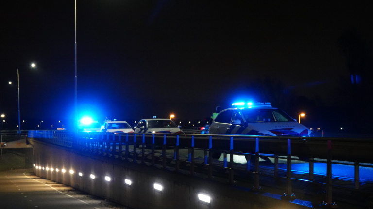 Politieauto's met zwaailichten op een snelweg 's nachts.