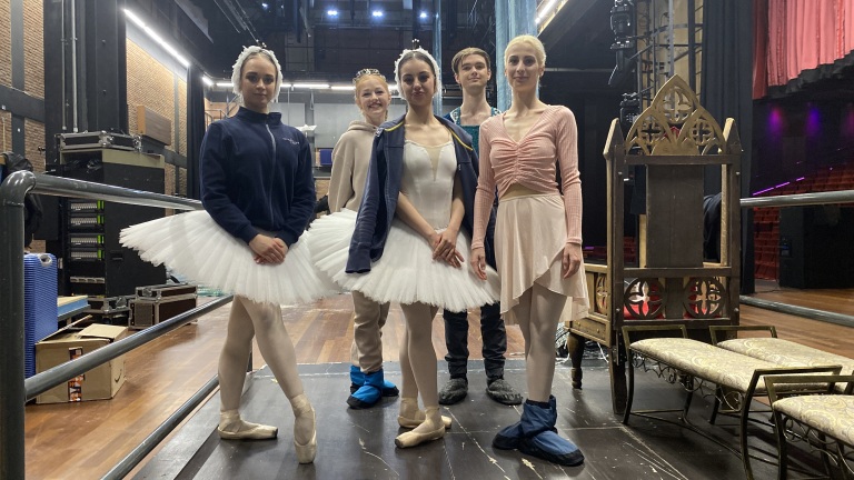 Balletdansers backstage in kostuum op een theaterpodium.