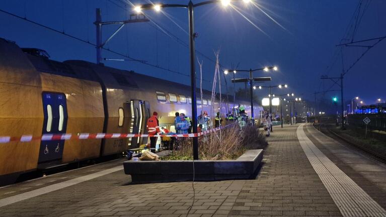 Trein bij perron met hulpdiensten en rood-wit afzetlint in de avond.