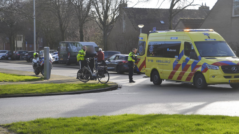 Een ambulance en politieagenten op straat in een woonwijk bij een voertuigincident.