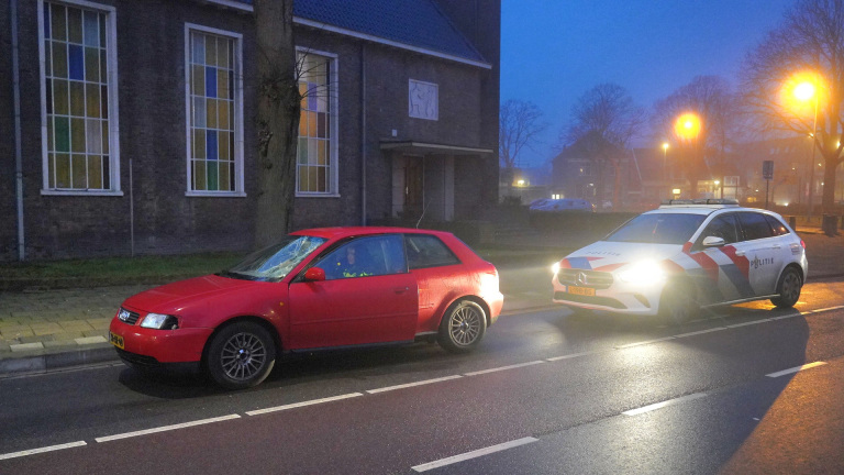 Rode auto en politieauto geparkeerd langs de weg bij nacht.