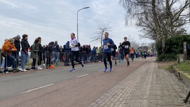 Hardlopers tijdens een wegwedstrijd met toeschouwers langs de kant van het parcours.