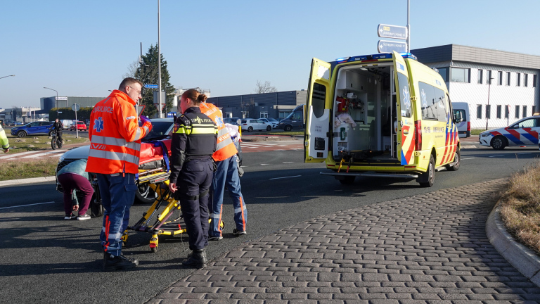 Twee ambulancepersoneelsleden en een politieagent bij een brancard naast een ambulance op straat.