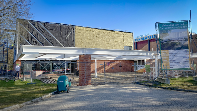 Uitbreiding van sporthal Het Vennewater in Heiloo, met bouwmaterialen en informatiebord.