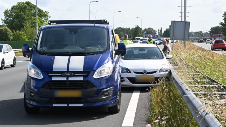 Een stilstaande auto en bestelbus langs de snelweg met personen ernaast, betrokken bij een verkeerssituatie.