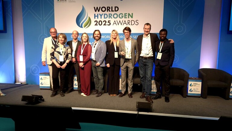 Een groep mensen poseert voor een foto bij een podium tijdens de World Hydrogen 2025 Awards, genomen in een conferentieomgeving met een groot bord met het evenementlogo op de achtergrond.