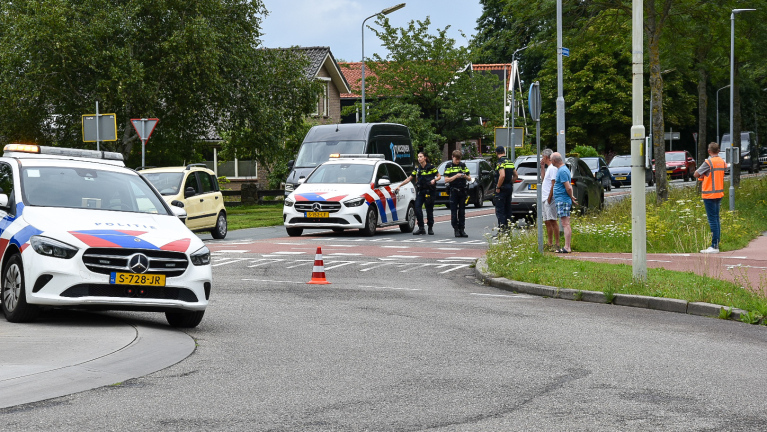 Politieauto's en agenten staan bij een verkeersongeluk met auto's geblokkeerd op de weg.