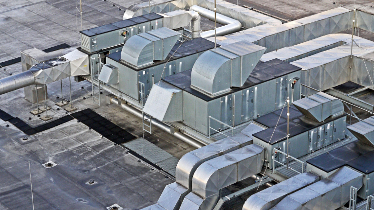 Ventilatiesysteem op een plat dak met meerdere grote, rechthoekige metalen units en buizen.