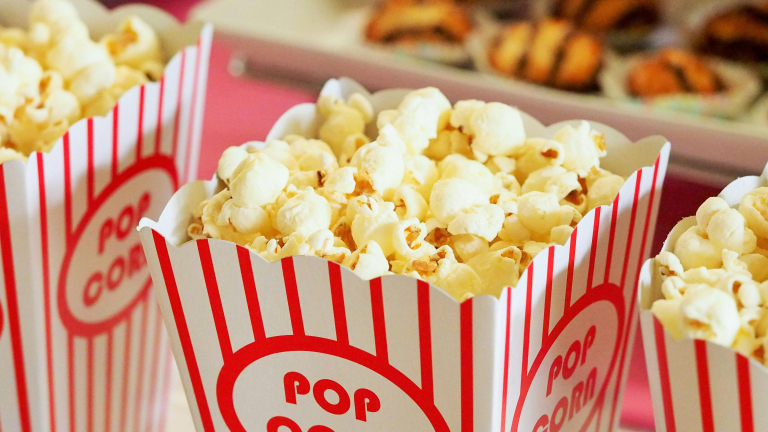 Bakjes met popcorn gevuld met witte, gepofte korrels en rode strepen op de achtergrond.