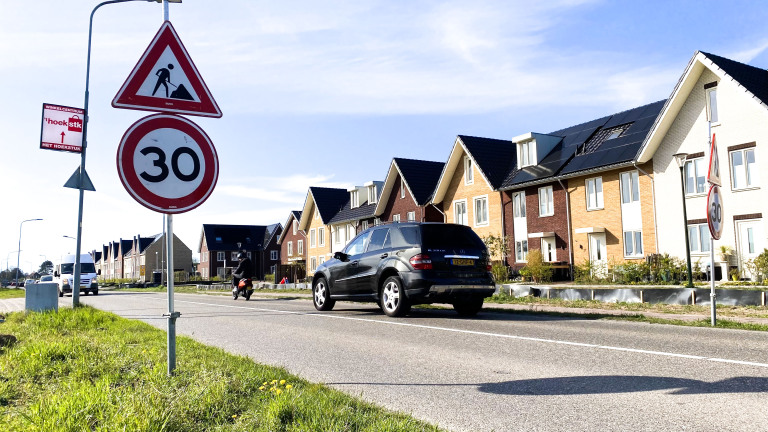 Een straat met een snelheidslimiet van 30 km/u en een bouwverkeersbord, omgeven door moderne rijtjeshuizen met zonnepanelen op de daken.