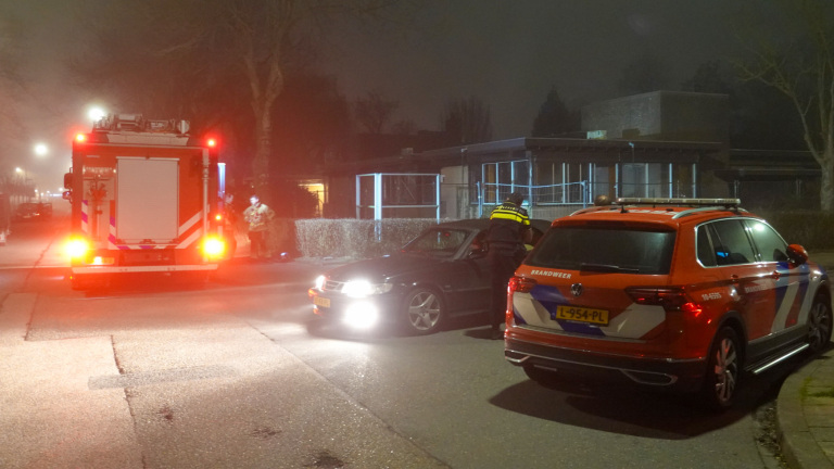 Politie en brandweer op een donkere straat met een brandweerwagen en een politieagent die met een automobilist praat.