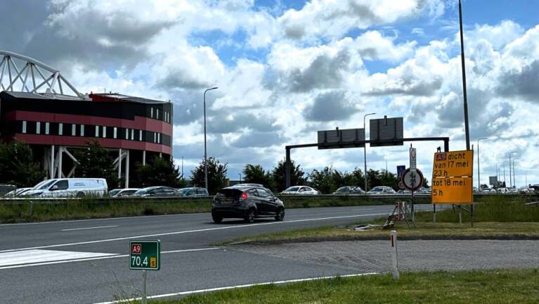 Auto op snelweg A9 naast bord dat tijdelijke wegafsluiting van 17 mei 23 uur tot 18 mei 5 uur aankondigt.