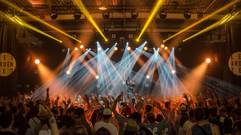 Publiek juicht tijdens een concert met felle lichten op het podium en een artiest die optreedt.