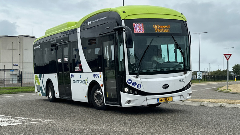 Witte Connexxion-bus met groene dakrand, lijn 163 naar Utrecht Station, rijdt op een rotonde