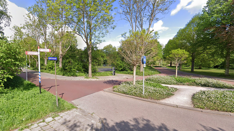 Kruising van rood fietspad in groen park met fietsroutebord en straatnaambord “Kruienland”