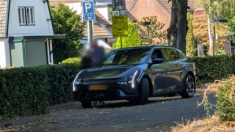 Zwarte auto geparkeerd langs een woonstraat met borden “P” en “let op: 1ar rechts heeft voorrang”