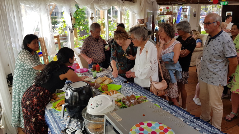 Mensen staan in de rij bij een buffet tijdens een bijeenkomst in een goed verlichte ruimte.