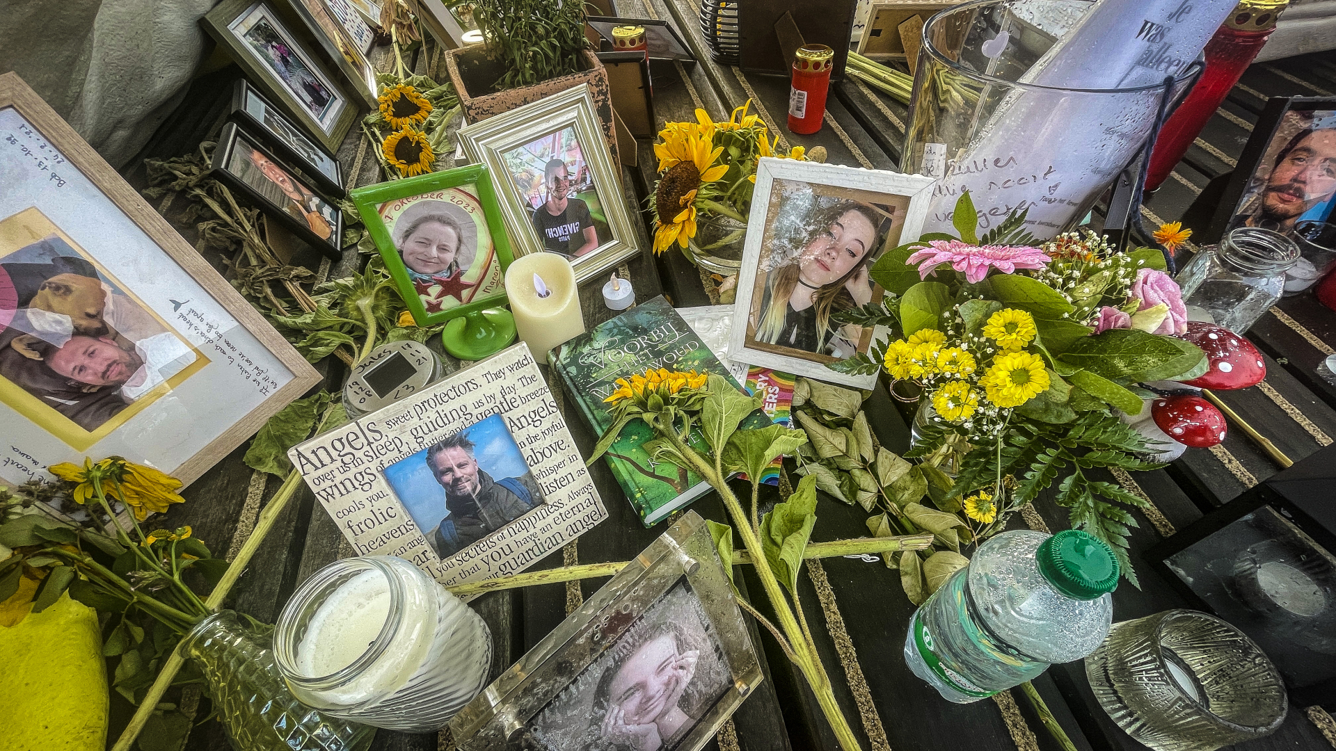 Herdenkingshoek met fotolijsten, kaarsen en bloemen op een tafel.