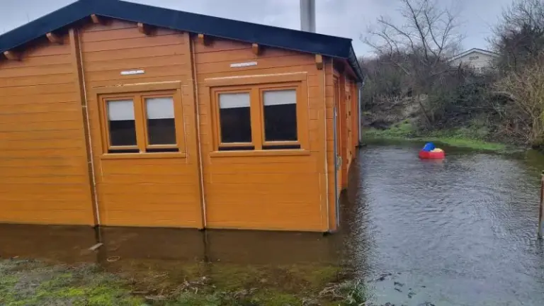 Houten huis omringd door overstromingswater.