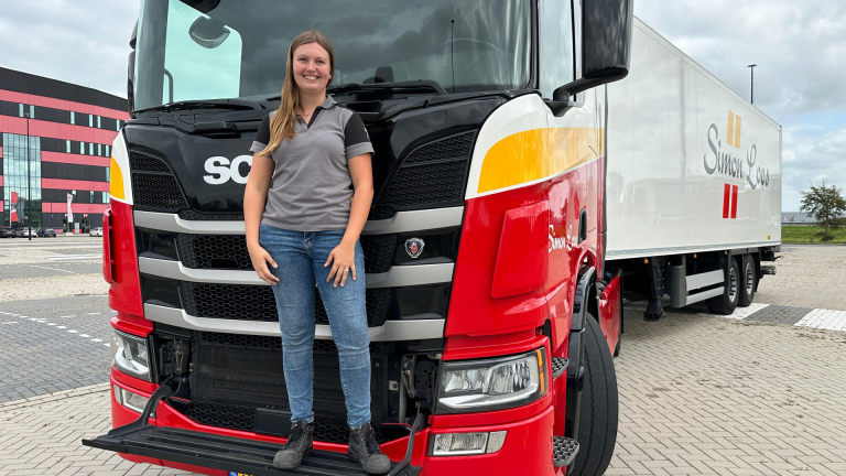 Vrouw poseert voor een rode Scania-vrachtwagen van Simon Loos.