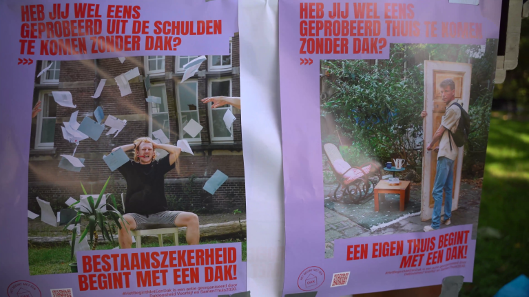 Twee posters met de tekst "Heb jij wel eens geprobeerd uit de schulden te komen zonder dak?" en "Heb jij wel eens geprobeerd thuis te komen zonder dak?". Op de linker poster zit een man tussen vliegende papieren en op de rechter poster staat een man met een deur. Beide teksten eindigen met "met een dak!".