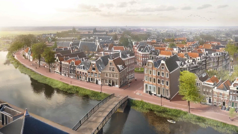 Luchtfoto van een schilderachtig Nederlands dorp met grachtenpanden, een rivier en een brug, omlijst door groen en boomrijke straten.