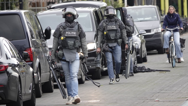 Gewapende politieagenten in tactisch uniform lopen in een straat.