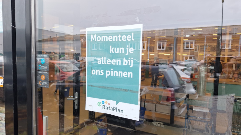 Een winkelraam met een bord waarop staat dat je momenteel alleen kunt pinnen bij RataPlan.